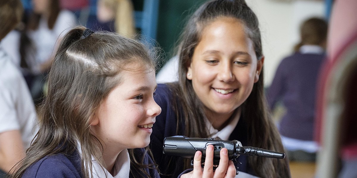 A group of diverse students engaged in a theatre workshop, surrounded by colourful props and stage equipment.