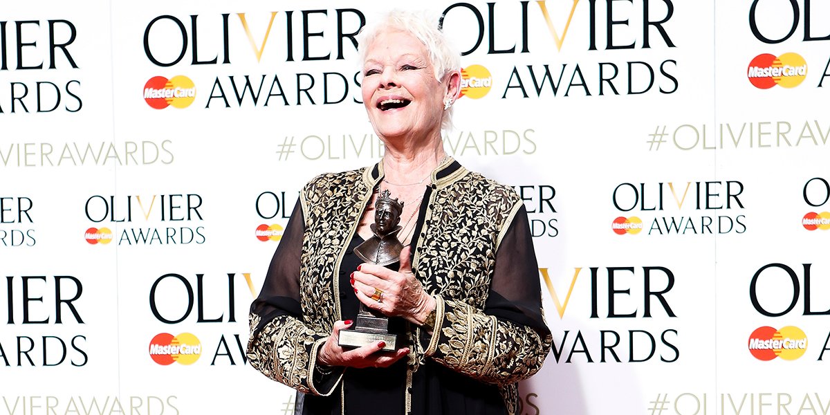 Dame Judi Dench wearing Asprey Oak Leaf Diamond earrings, smiling against a neutral background.
