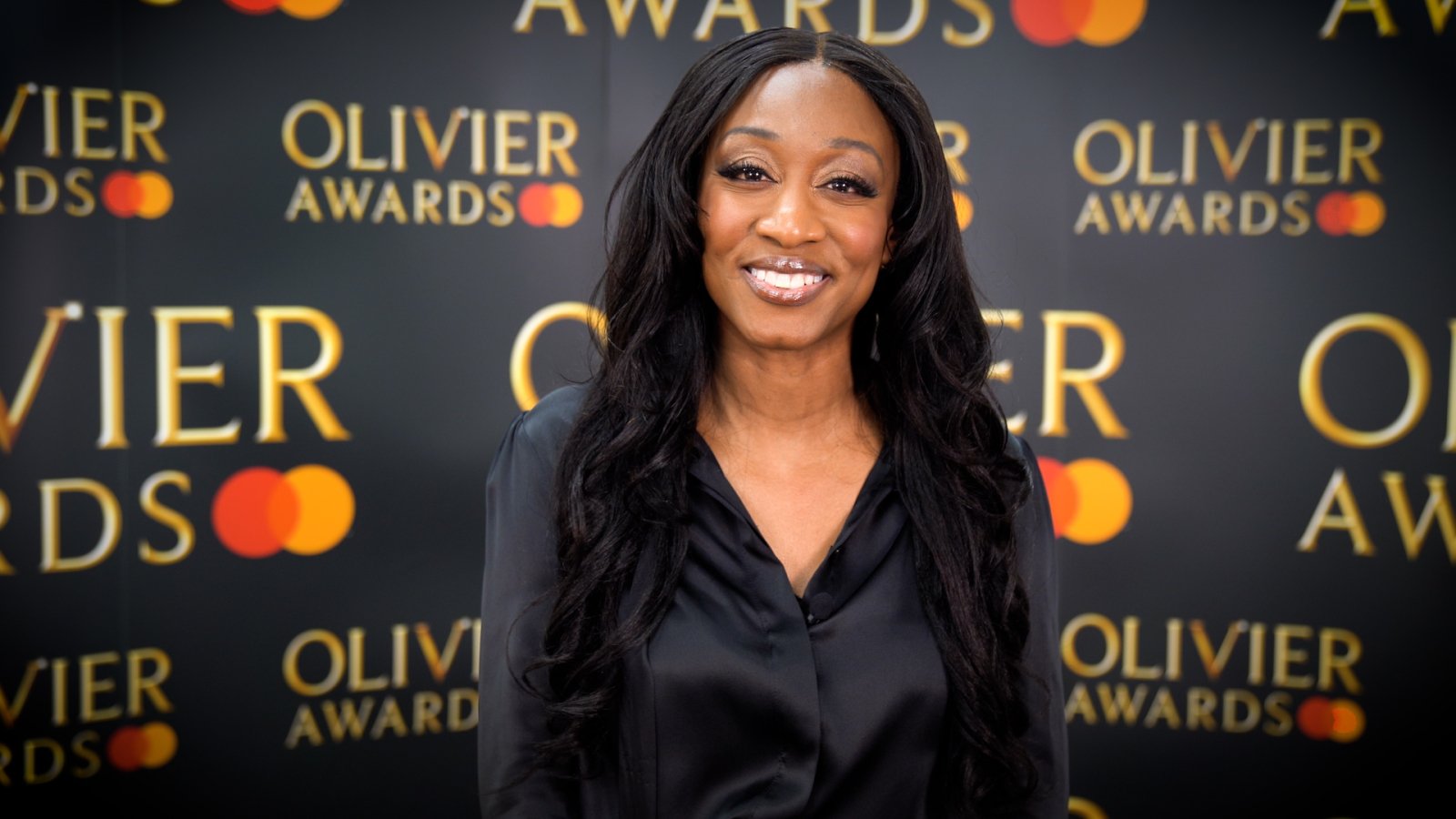 Beverley Knight stands in front of a background showing multiple Olivier Awards logos