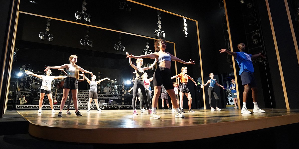 Children learning dance with cast of Tina The Tina Turner Musical