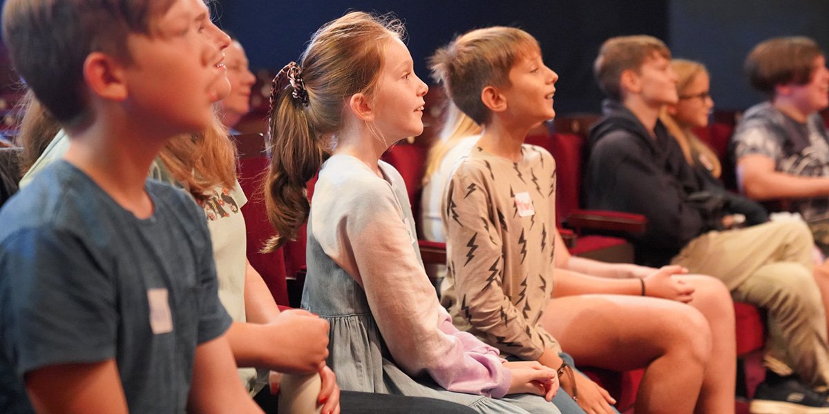 A row of seated children enjoying the theatre