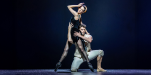 Mary, Queen of Scots, in an elaborate historical costume, stands poised against a dark, textured background.